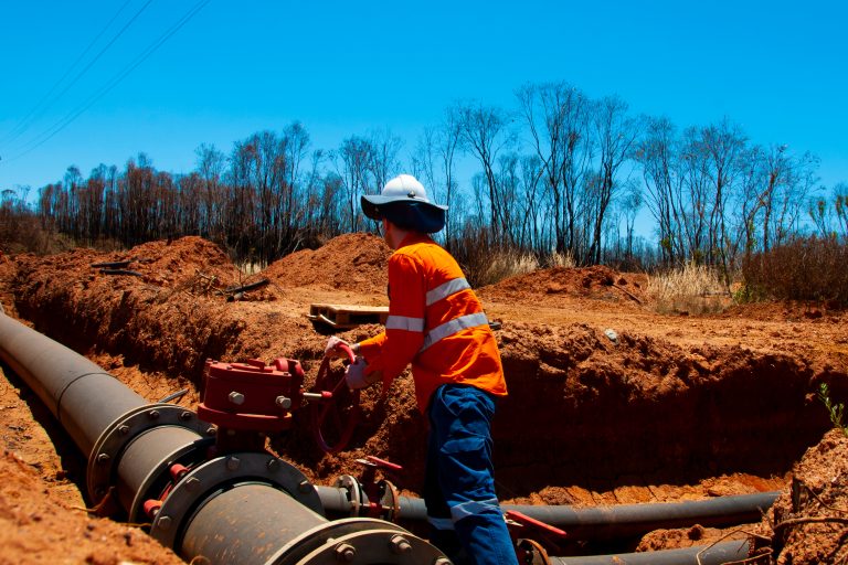 Field technician operating a water pipeline valve in a trench during maintenance works for Rous County Council